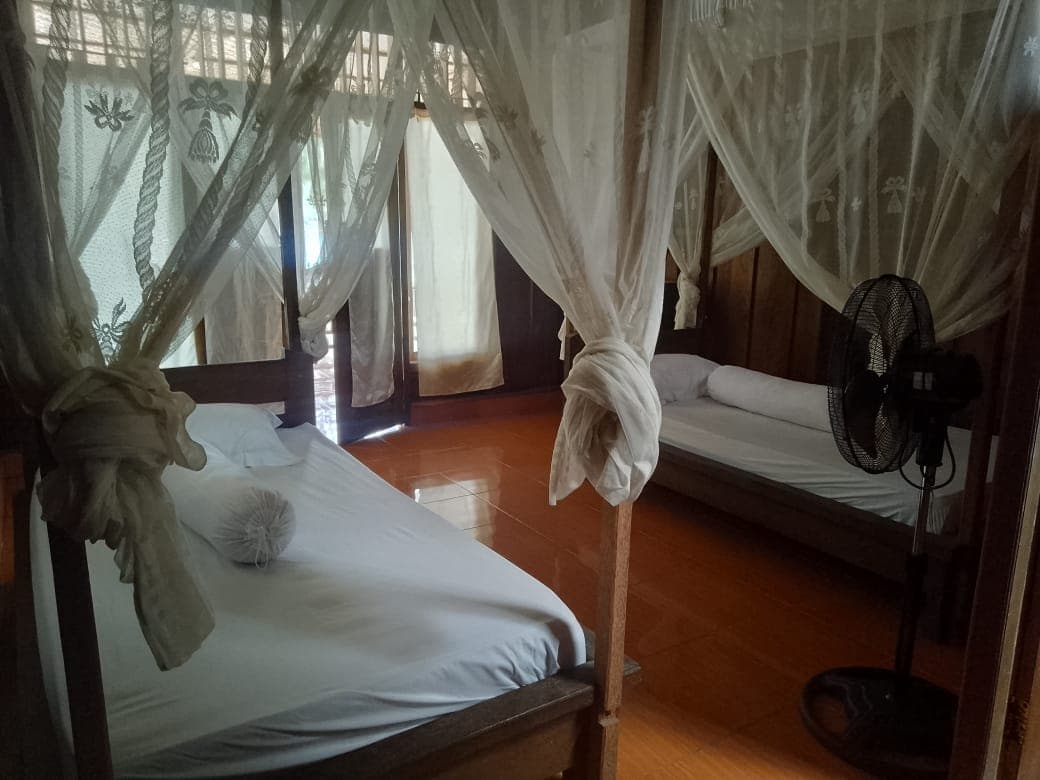 Fadhila Cottages – bungalow interior with fan and mosquito net