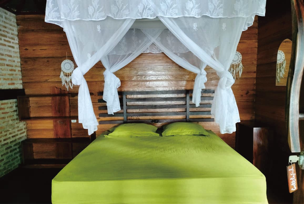 Malenge Indah – bungalow interior with king bed and mosquito net