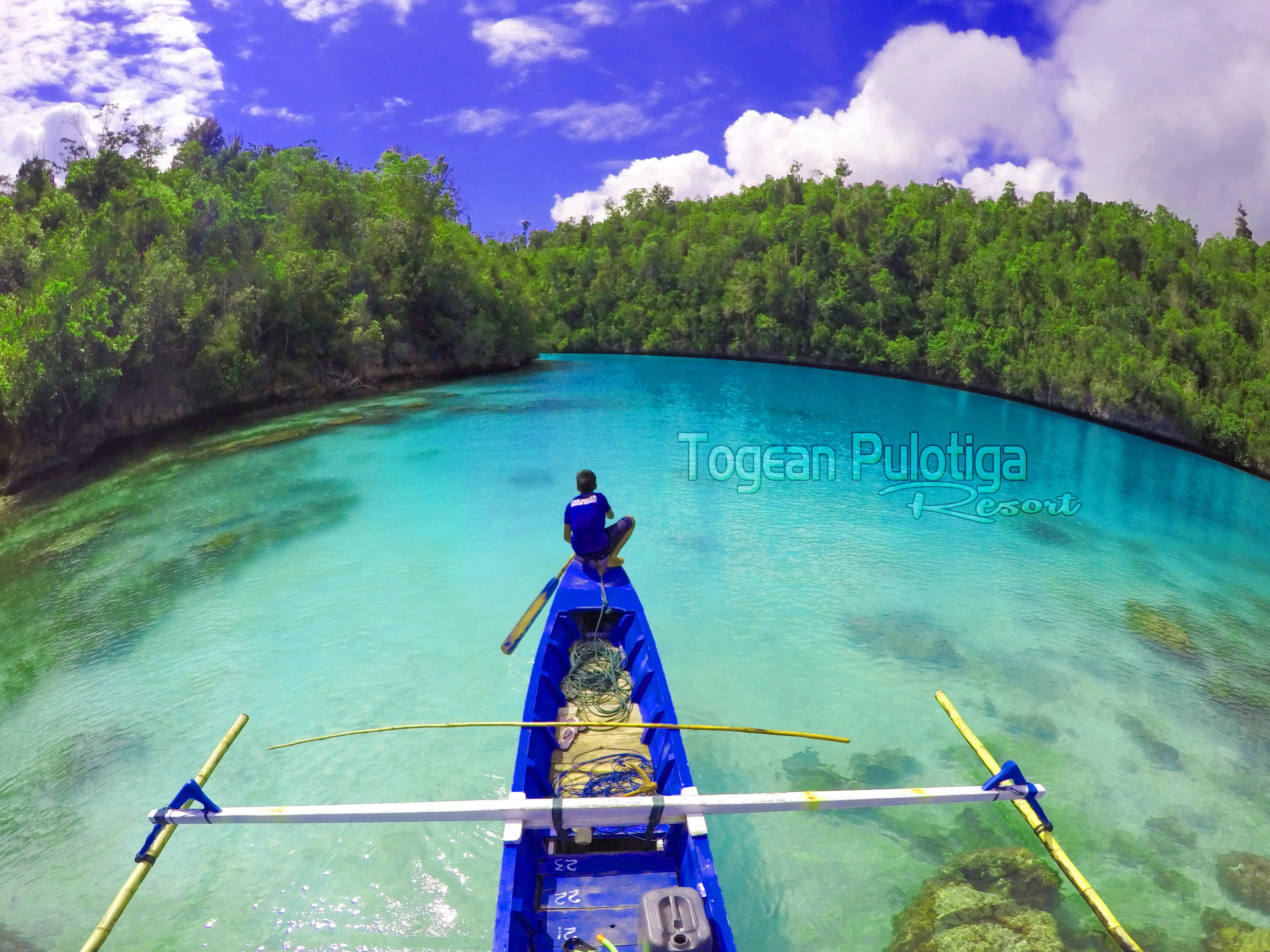 Togean Pulotiga Resort – outrigger boat gliding into the emerald lagoon near the resort